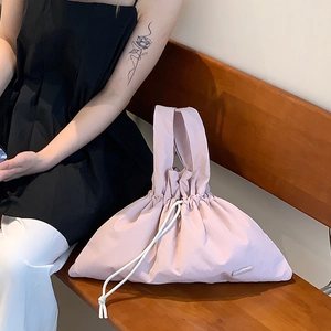 Detail of light pink puffy nylon handbag featuring a drawstring closure and soft texture