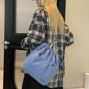 Adjustable drawstring backpack in light blue nylon fabric shown worn on back for daily commute