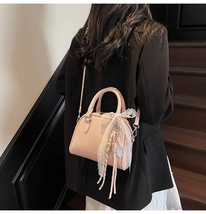 Pink bowling bag detail with lace bow and tennis racket charm worn by a model