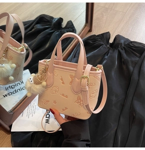 Close-up of pink embossed tote bag with puppy patterns and white plush lamb charm