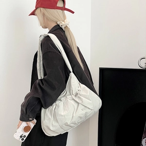 Detail view of large white pleated nylon tote bag featuring drawstring side closures