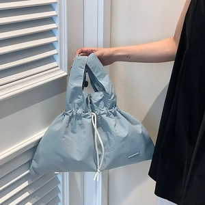 Close-up of light blue drawstring nylon bag with textured pleated details and branded tag