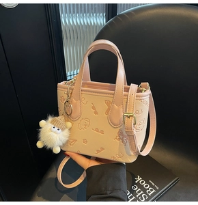 Detail of pink embossed crossbody bucket bag featuring cute floral patterns and plush charm