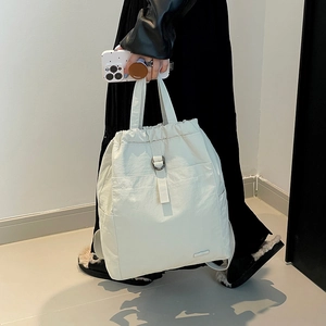 Detail eines beigen Nylon-Rucksacks mit Kordelzugverschluss und metallischer D-Ring-Schnalle