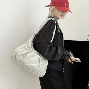 Detail view of cream pleated nylon shoulder bag showing puffy texture and drawstring design