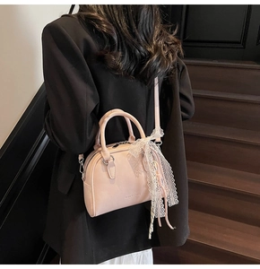 Pink bowling bag with lace bow detail shown being carried over the shoulder by a model