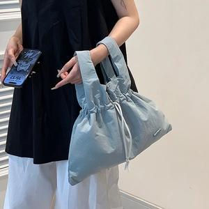 Close-up of light blue nylon handbag with drawstring closure and dual handles