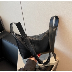 Detail view of the black Hobo dumpling bag with wide adjustable shoulder strap and leather texture