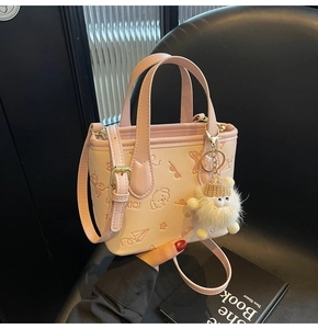 Close-up of pink bucket bag featuring cartoon embossing and a plush monster charm