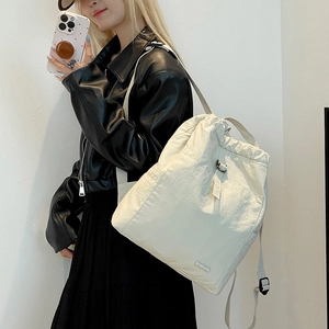 Detailansicht des cremefarbenen Nylon-Rucksacks mit Kordelzug und schwarzer Schnalle