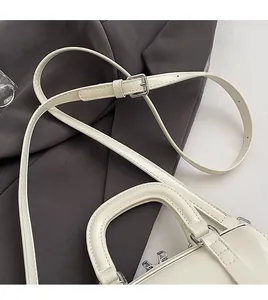 Close-up of adjustable strap and silver metal buckle on a beige leather Boston bag