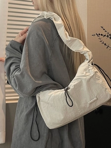 Chic beige nylon cloud bag with ruched scrunchie shoulder strap worn by a model