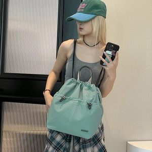 Detail view of mint green lightweight drawstring backpack on model in a minimalist room