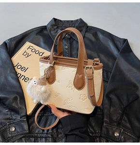 Detail of embossed floral pattern on mini bucket bag with leather trim and charm