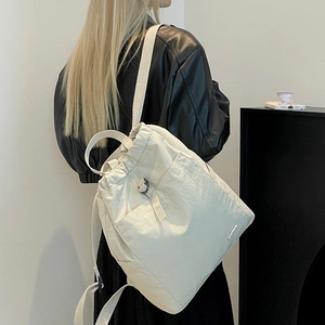 Detail eines cremeweißen Nylon-Rucksacks mit Kordelzug und verstellbaren Trägern