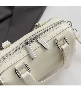 Detail of silver dual zipper closure and premium texture on white Boston handbag