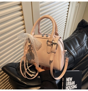 Detailed shot of a pink glossy bowling bag with lace bow and metal charms on black leather