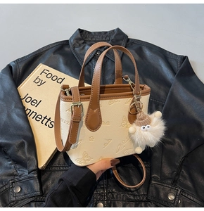 Detail of floral embossed cream and brown crossbody bucket bag with sheep plush charm