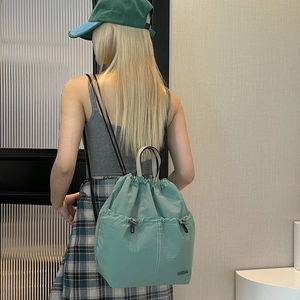 Detail of mint green drawstring backpack showing the dual front pockets and storage space