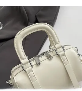 Detail of cream white Boston bag with silver zippers on dark grey suit fabric