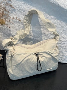 Minimalist beige pleated nylon cloud bag with ruched shoulder strap and drawstring detail