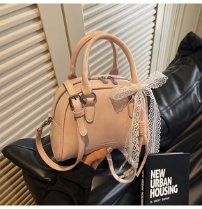 Detailed shot of pink gloss PU bowling bag with lace bow and adjustable strap on sofa