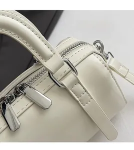 Close-up of cream Boston bag featuring silver zippers and reinforced leather handles