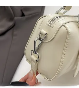 Detail of cream leather handbag showing silver spring clip and smooth metal zipper