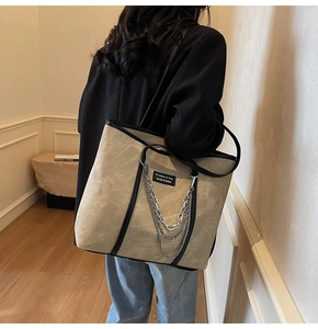 Détail du grand sac cabas en daim beige avec bordures en cuir noir et chaîne
