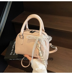 Pink glossy bowling bag featuring a white lace bow and charms on a wooden staircase