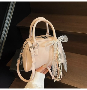 Detailed view of pink Boston bag with lace bow decoration on dark wooden stairs