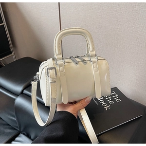 Detail of a creamy white Boston handbag with glossy finish and silver hardware details