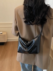 Elegant black glossy leather slouchy crossbody bag styled with casual blazer and jeans