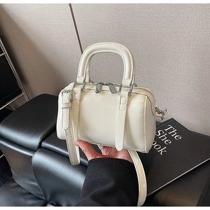 Close-up of cream mini Boston bag with silver zippers and adjustable crossbody strap