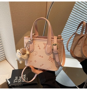 Detailed close-up of pink embossed bucket bag featuring floral patterns and a plush sheep charm
