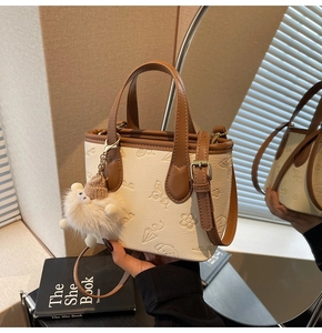 Detail of color-block bucket bag with embossed patterns and plush ball pendant