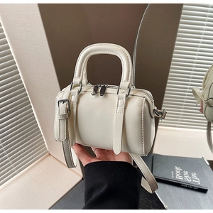 Detail of silver dual zippers and fine hardware on white mini Boston cylinder bag