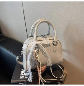Close-up of light grey bowling bag with white lace bow and tennis racket charm detail