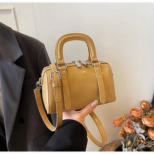 Close-up of yellow Boston handbag with smooth leather texture and silver hardware details