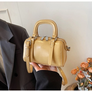 Detail of yellow mini Boston handbag showing smooth synthetic leather and silver metal zippers