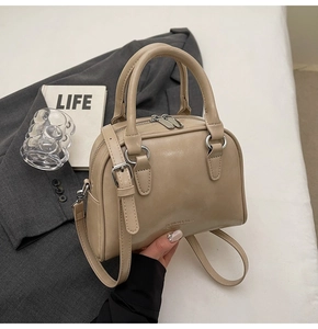 Detailweergave van abrikoos Boston tas met zilveren gespen op een grijze blazer