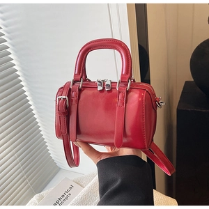 Detail of red glossy patent leather Boston bag with silver hardware and dual zippers