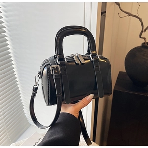 Close-up of black glossy Boston bag with silver hardware and adjustable shoulder strap