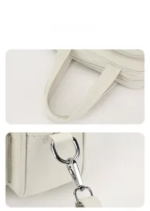 Detail view of reinforced handles and polished metal zippers on a white nylon utility tote