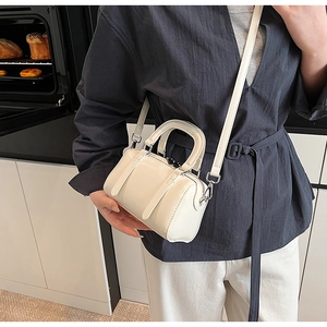 Detailed view of a white mini Boston bag with glossy finish and silver hardware
