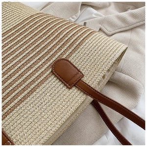 Close-up of striped straw weave texture and brown leather strap on a beach tote bag