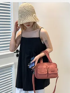 Close-up of pink nylon utility crossbody bag featuring dual front zipper pockets and top handles