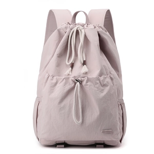 Detail of light pink nylon backpack featuring drawstring closure and rubber brand logo