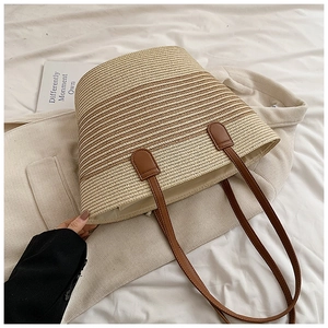 Detail of striped woven straw tote with brown PU leather handles and magnetic closure