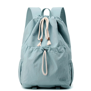 Macro detail of the mint green nylon fabric and thick drawstring tassel on the backpack